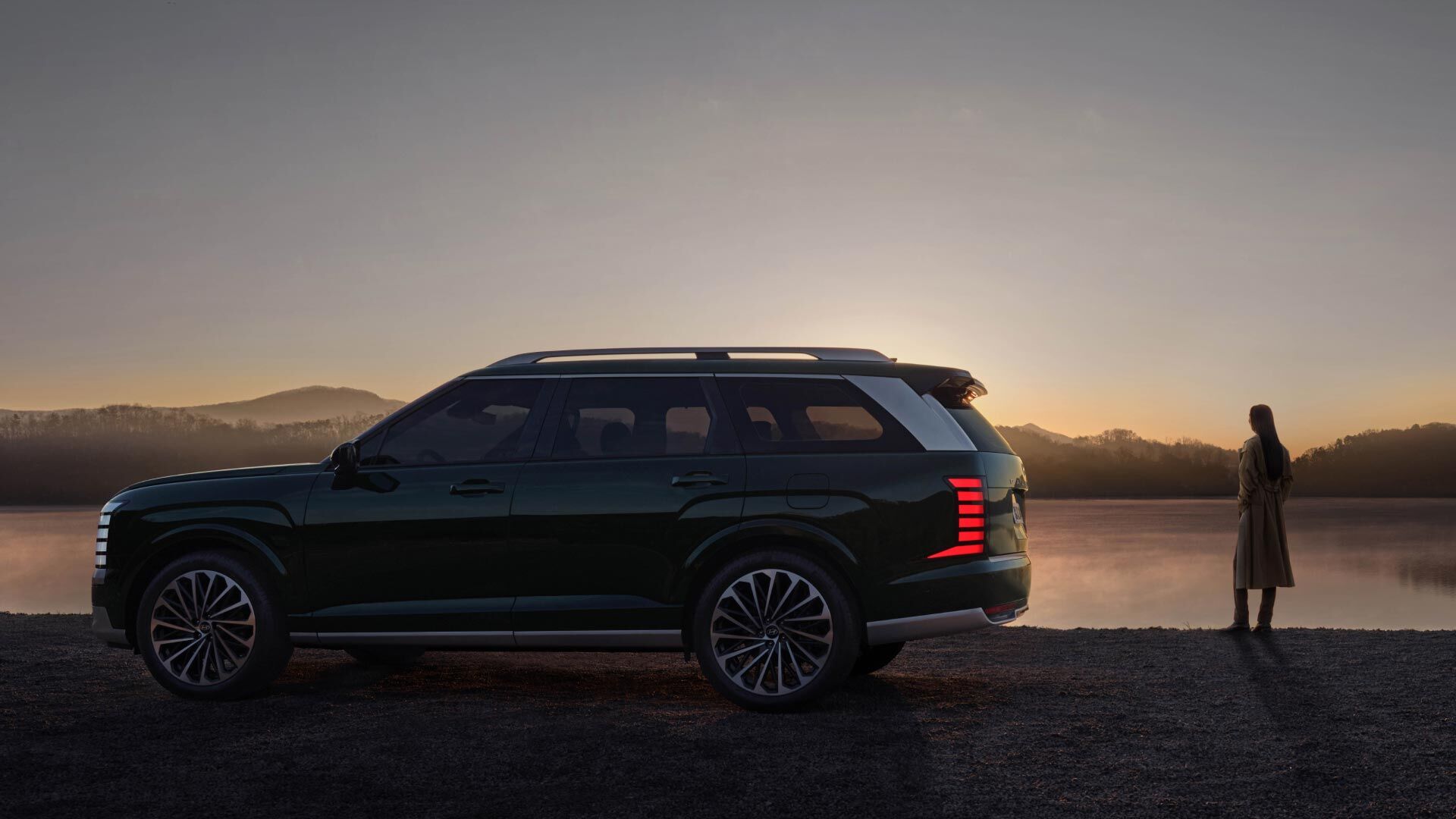 Side-front view of orange Grandi10 with lakeside view at night